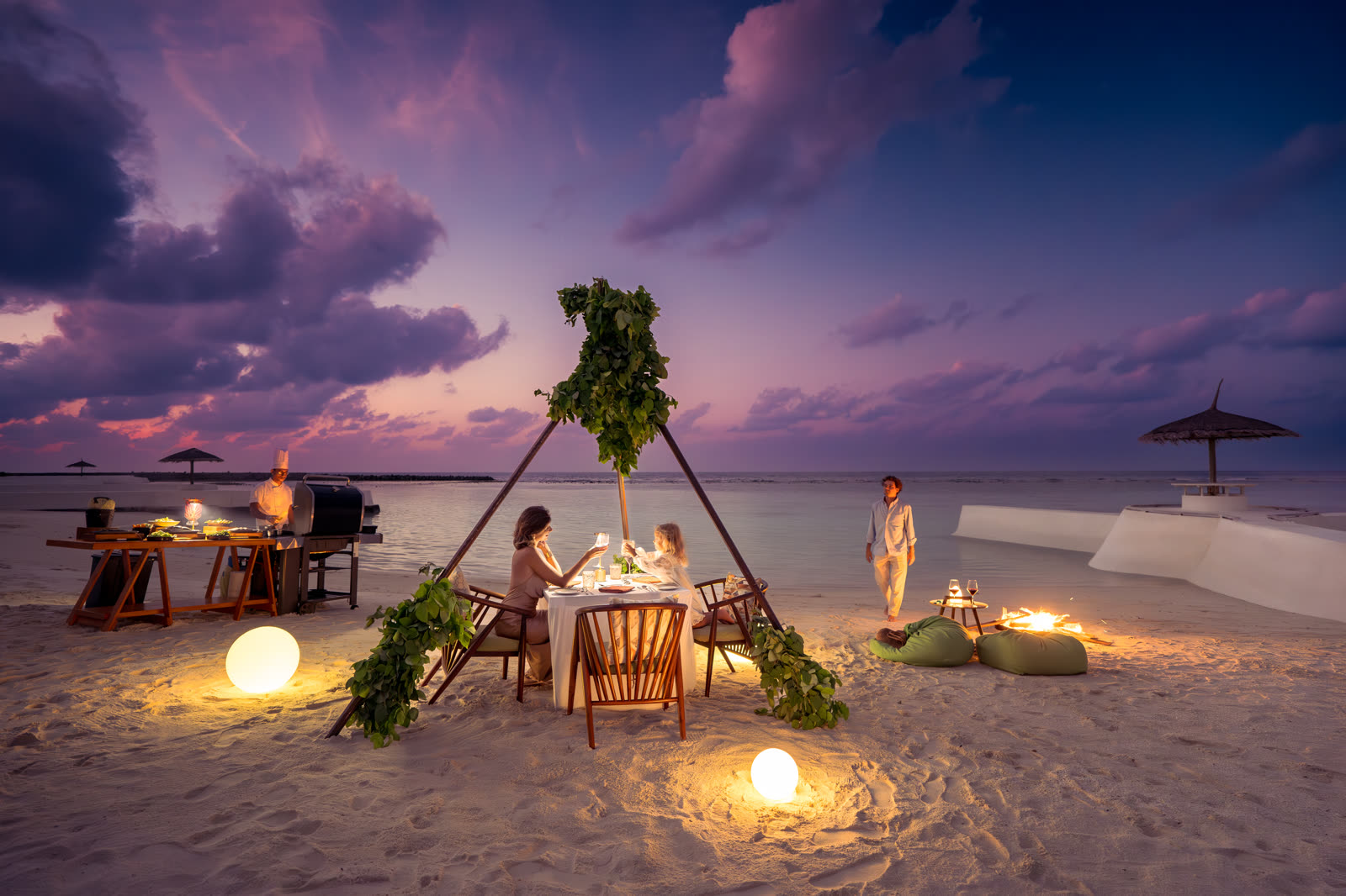 Private beach dinner under a violet sunset